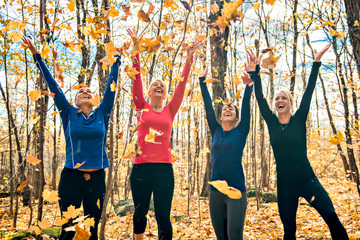 woman group out running together in an autumn park they run a race or train in a healthy outdoors lifestyle concept