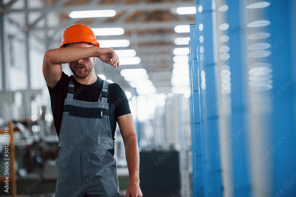 Taking off hard hat. After the work. Industrial worker indoors in factory. Young technician Taking off hard hat. After the work. Industrial worker indoors in factory. Young technician