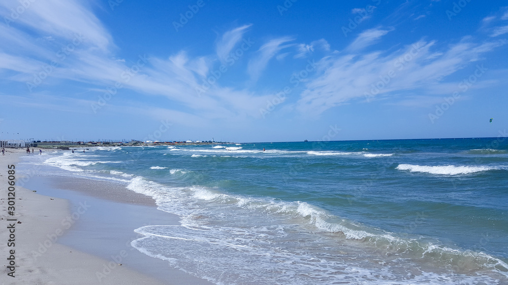 The sea is agitated. Beautiful waves on a sandy beach. Sea, waves, and blue sky.