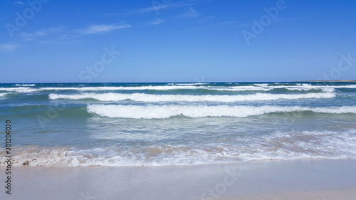 The sea is agitated. Beautiful waves on a sandy beach. Sea  waves  and blue sky.