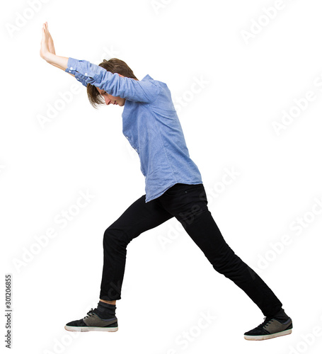 Konstfotografi Determined teenage guy making effort as pushing an heavy invisible object isolated on white background