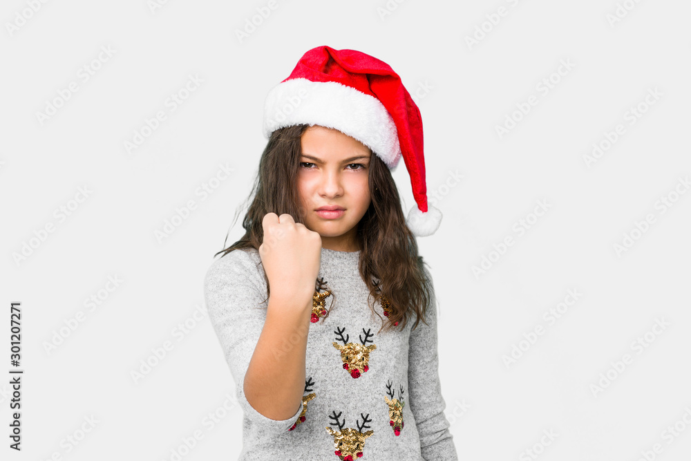 Little girl celebrating christmas day showing fist to camera, aggressive facial expression. Little girl celebrating christmas day showing fist to camera, aggressive facial expression.