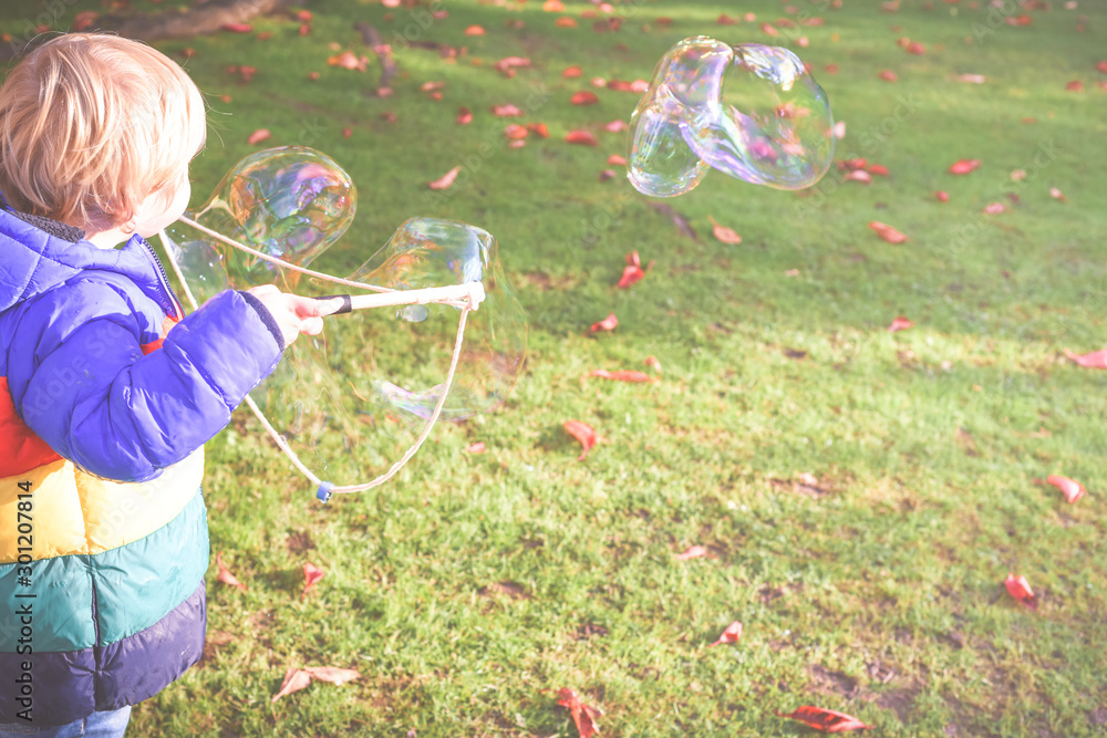 Child playing outside in a garden during day time with bubbles he is happy and running Child playing outside in a garden during day time with bubbles he is happy and running