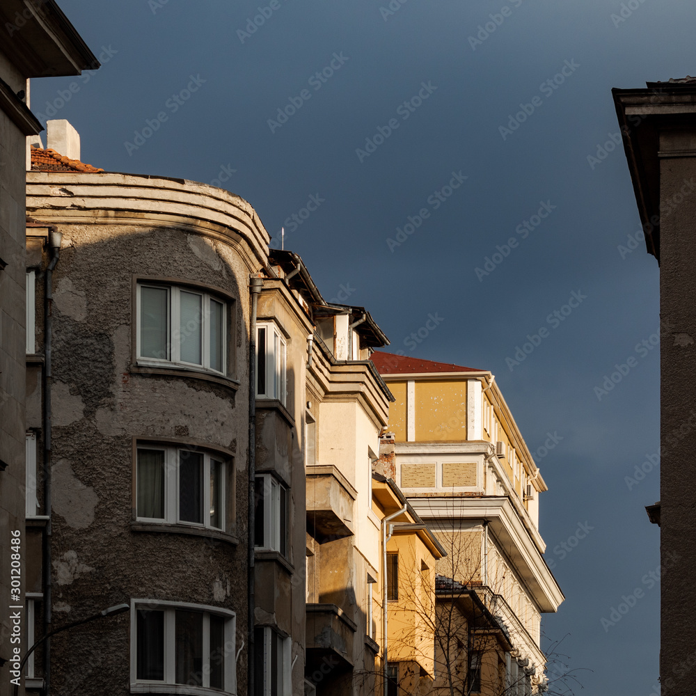 buildings illuminated by the sun, with grey stormy sky