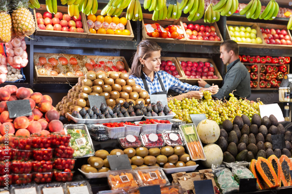 Woman selling grapes and fruits on the supermarket