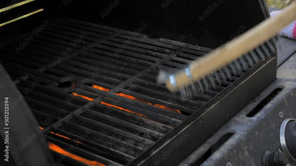 Wire metal brush scraping a bbq grill to clean it Wire metal brush scraping a bbq grill to clean it