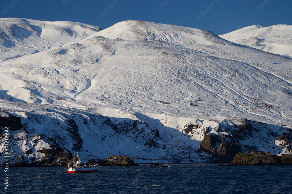 Iceland cliffs view from the sea in winter including boat Iceland cliffs view from the sea in winter including boat