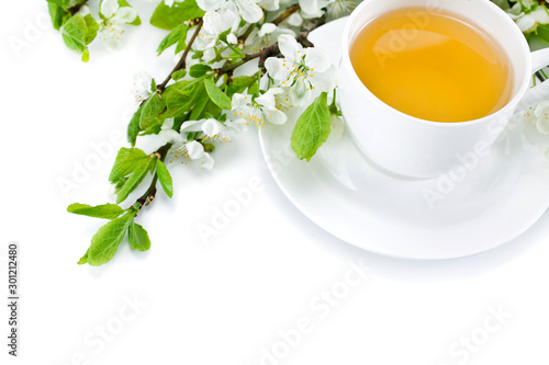 Green tea in a ceramic cup with branches of blossoming apple tree isolated on a white background. Top view.