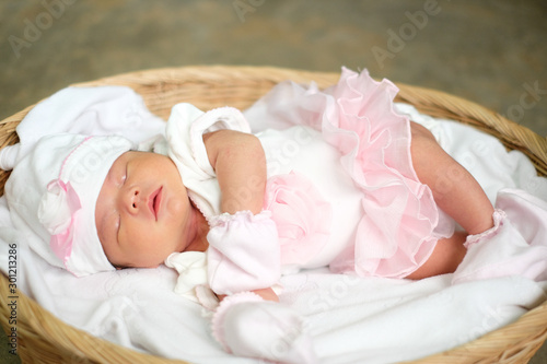 Asia newborn in white dress sleeping in basket photo