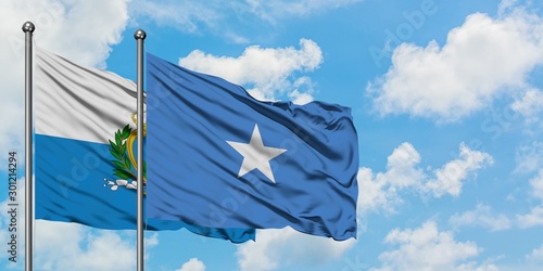 San Marino and Somalia flag waving in the wind against white cloudy blue sky together. Diplomacy concept, international relations.