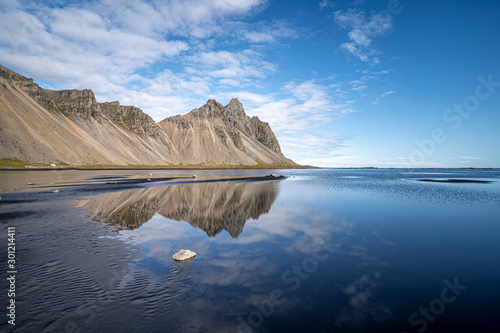 vestrahorn in southern Iceland, mirroring in calm water over black volcanic beach, landscape  photo