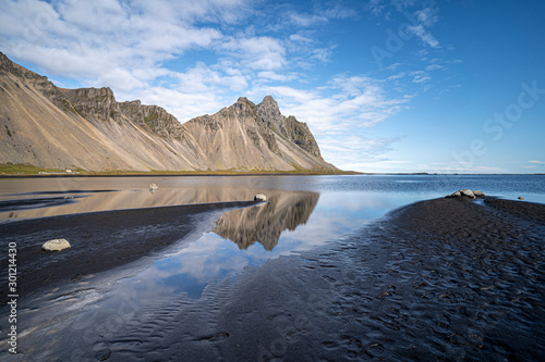 vestrahorn in southern Iceland, mirroring in calm water over black volcanic beach, landscape  photo