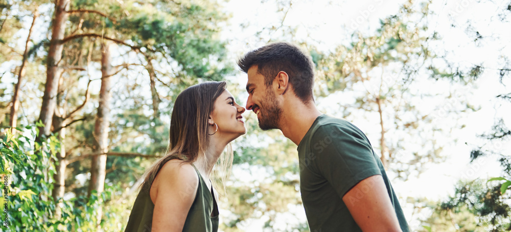 © standret - Side view. Beautiful young couple have a good time in the forest at daytime © standret - Side view. Beautiful young couple have a good time in the forest at daytime