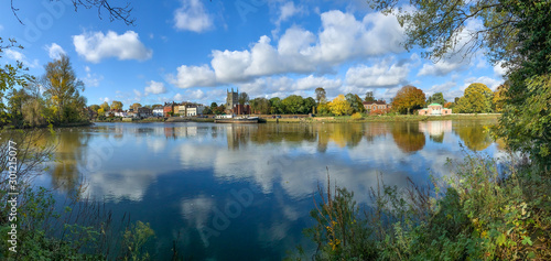 Panoramic view of Thames river in autumn season, skyline of vibrant trees reflected in water in a sunny day in London