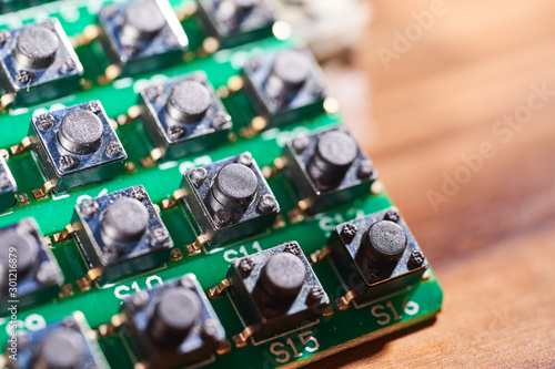 Many black small buttons on a green printed circuit board photo