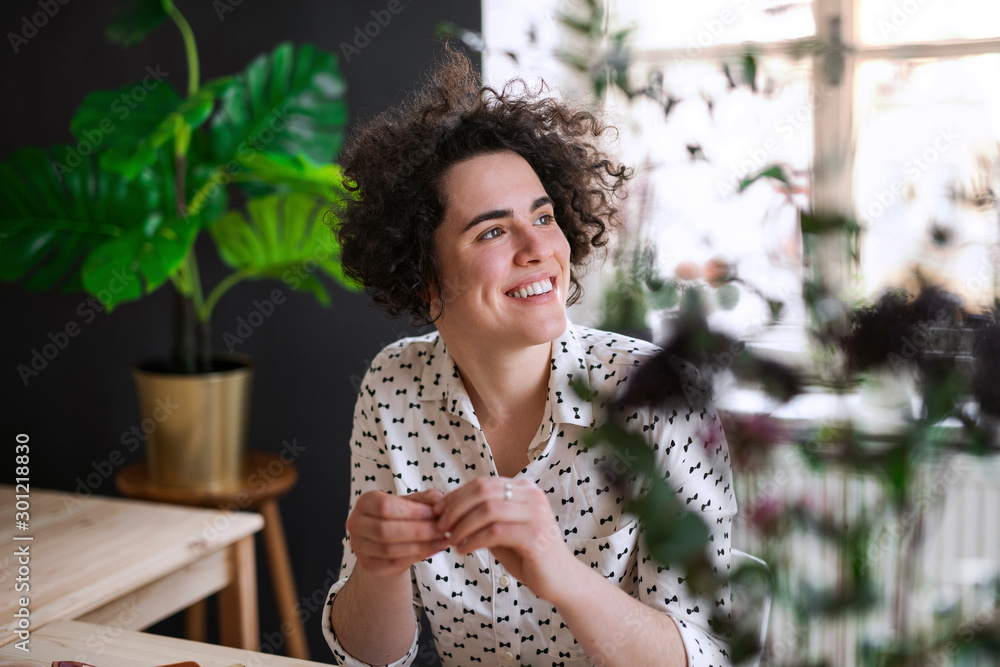 Smiling young woman sitting at table looking sideways Smiling young woman sitting at table looking sideways