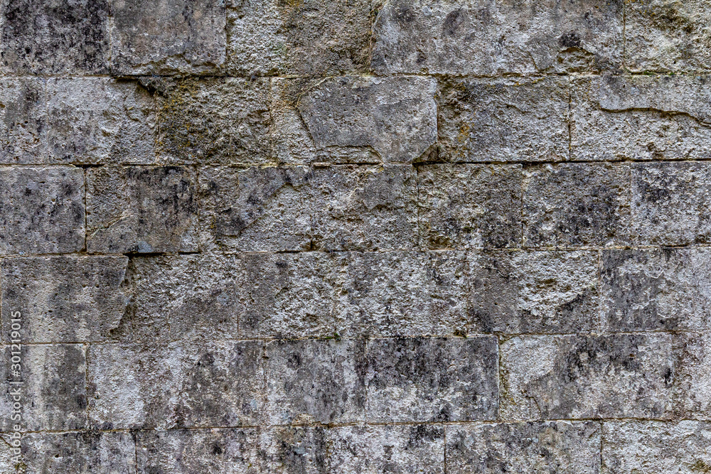 old grey rectangular stone wall with many rough edges