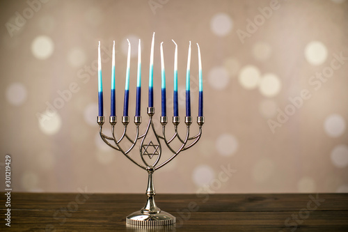 A silver menorah for the Jewish holiday Hanukkah with eight candles not yet lit on a beige background with copy space