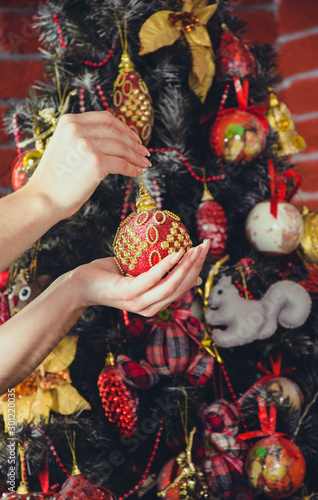 Little girl holding a fir-tree toy. Christmas and new year concept. Child's hands holding beautiful christmas toy on the background of the Christmas tree