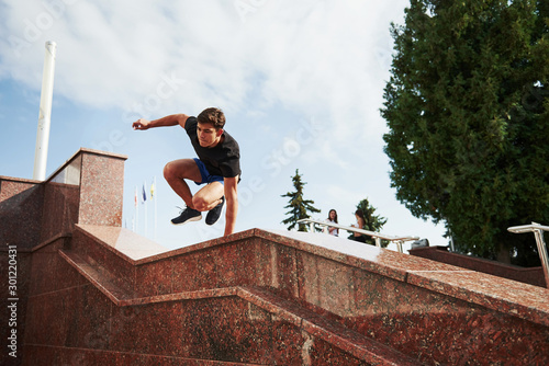 Above the obstacle. Young sports man doing parkour in the city at sunny daytime