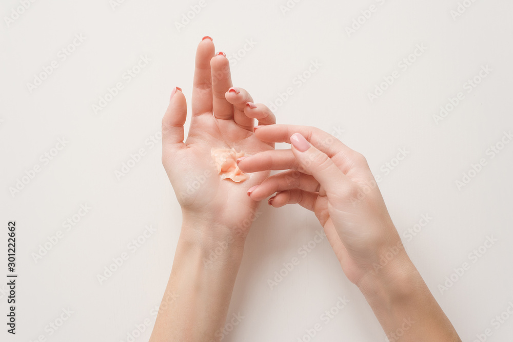 The girl distributes moisturizing cream on her hands. Hands on a white background with a jar of white cream. Flat lay top view minimalism style. Beauty concept, dermatology cosmetic The girl distributes moisturizing cream on her hands. Hands on a white background with a jar of white cream. Flat lay top view minimalism style. Beauty concept, dermatology cosmetic