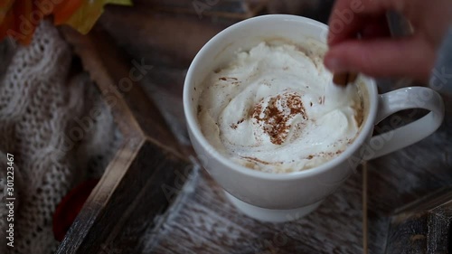 Mixing up hot chocolate with cream and cinnamon, tasty warm winter and autumn  drink