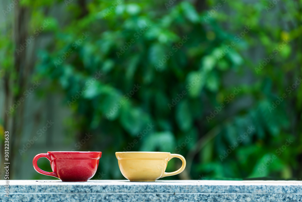 red and yellow ceramic coffee cup on marble table