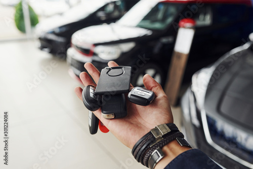 Keys from the cars lying on man's hand. Indoors in auto salon © standret