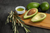 Fresh sliced avocado and olive oil on wooden background. Cosmetic oils, body and face care. Avocado oil ingredients. Natural ingredients. Olive oil and olive branches.