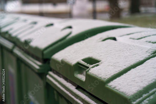 First snow in city Moscow. Calmness and freshness. Green waste bins are covered by first snow. They look clean. Consepts of cleaness and freshness. photo