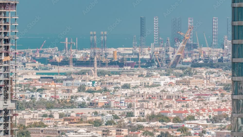 Aerial evening view from Downtown of Dubai timelapse with skyscrapers, houses and port Rashid on a background, ships docking at sea port, UAE Aerial evening view from Downtown of Dubai timelapse with skyscrapers, houses and port Rashid on a background, ships docking at sea port, UAE