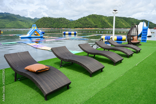 Modern black loungers on artificial lawn on poolside photo