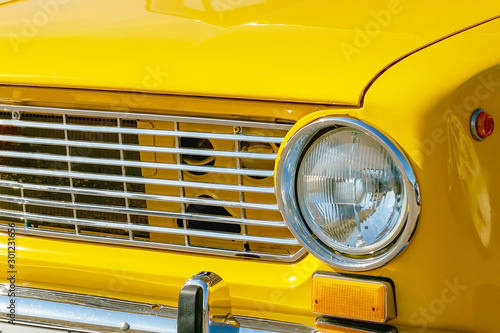 yellow retro car with chrome headlight, radiator grill and bumper