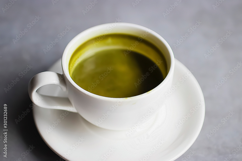 Matcha latte in a white cup on a gray background. Superfood concept. Matcha latte in a white cup on a gray background. Superfood concept.