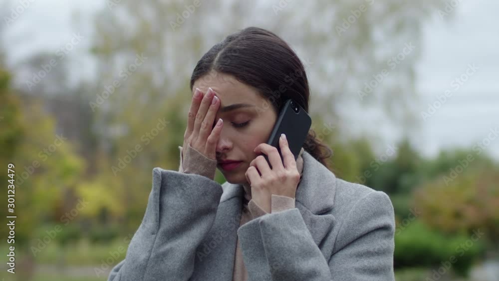 Closeup woman getting bad news on phone call outdoors. Upset brunette girl feeling sad after serious conversation. Closeup woman getting bad news on phone call outdoors. Upset brunette girl feeling sad after serious conversation.