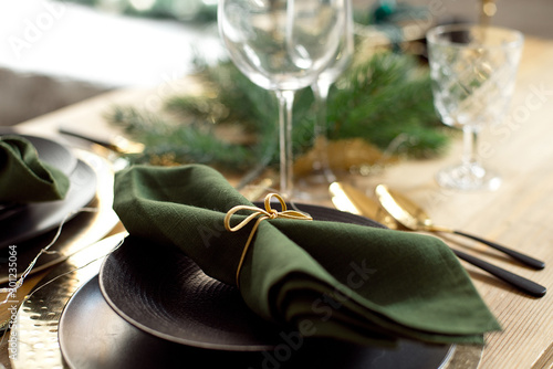 Christmas decoration with pine branches, table setting and candles on a dark Christmas tree background.