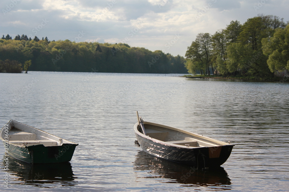 Obraz premium Two boats moored at the shore. A view of a calm lake.