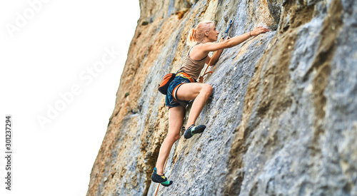 Slika na platnu young woman rock climber Climbing The Rock Having Workout In Mountains, searching, reaching and gripping hold on white background