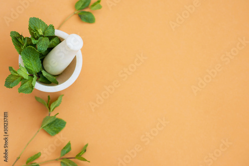 Ceramic mortar with a suitable pestle or grinder of food products, with mint herbs, for cosmetology and medicines on a beige background, with place for text