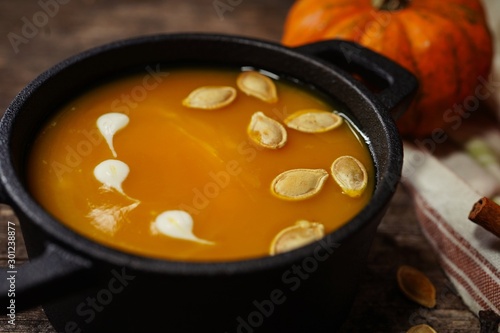 Homemade pumpkin soup on wooden autumn background