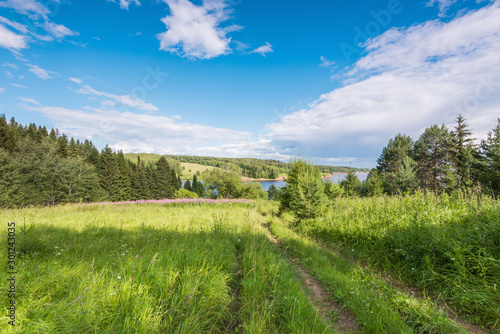 Beautiful panoramic view of the Kama river from the hill in the foreground green grass  summer blue sky with clouds.