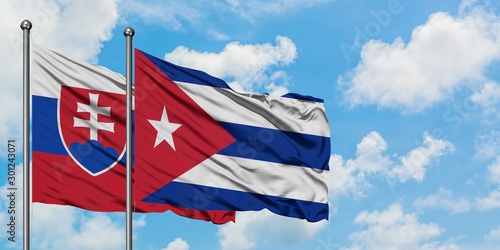 Photography Slovakia and Cuba flag waving in the wind against white cloudy blue sky together