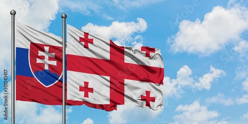 Photography Slovakia and Georgia flag waving in the wind against white cloudy blue sky together