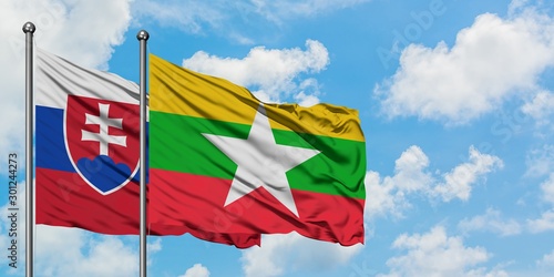 Photography Slovakia and Myanmar flag waving in the wind against white cloudy blue sky together