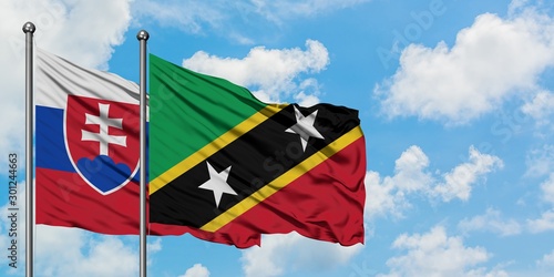 Photography Slovakia and Saint Kitts And Nevis flag waving in the wind against white cloudy blue sky together
