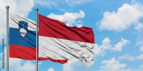 Slovenia and Indonesia flag waving in the wind against white cloudy blue sky together. Diplomacy concept, international relations.