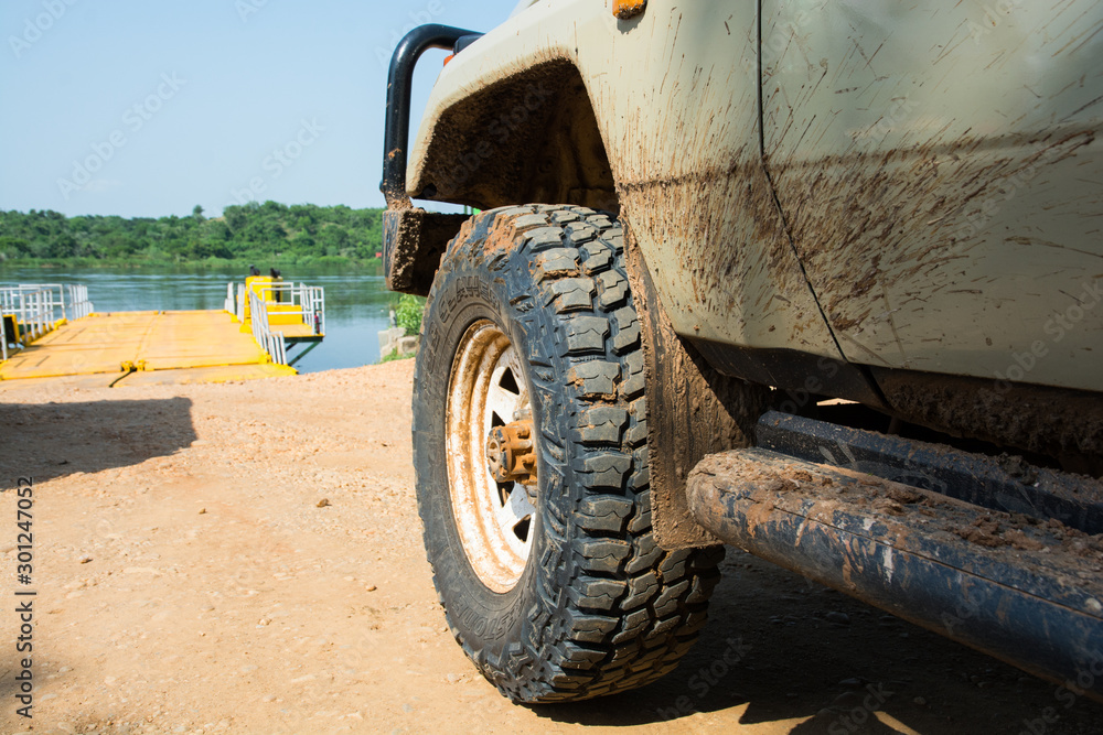 Dirty, stowed 4wd wheel after an adventurous offroad ride on wild paths through the soaked ground at Marchinson Falls, Uganda, Africa. Dirty, stowed 4wd wheel after an adventurous offroad ride on wild paths through the soaked ground at Marchinson Falls, Uganda, Africa.