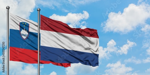 Slovenia and Netherlands flag waving in the wind against white cloudy blue sky together. Diplomacy concept, international relations.
