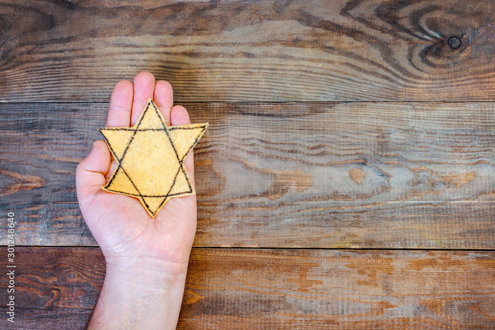 Male hand and star of David on a wooden board background. Holocaust Remembrance Day
