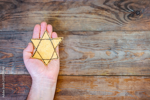 Obraz na płótnie Male hand and star of David on a wooden board background. Holocaust Remembrance Day w salonie